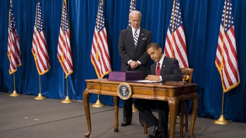 US Vice President Joe Biden stands with US President Barack Obama as he signs the American Recovery and Reinvestment Act at the Denver Museum of Nature and Science in Denver, Colorado, on February 17, 2009.