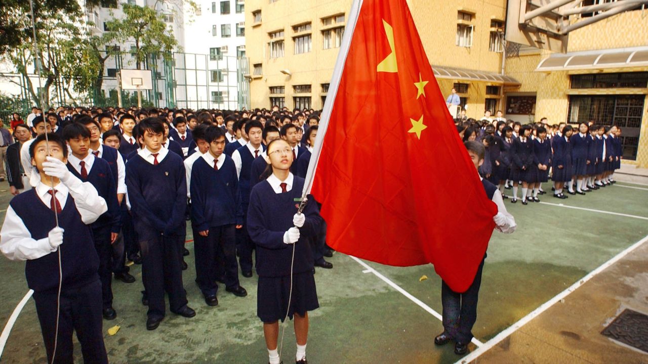 Students at the patriotic Heung To Middle School in Hong Kong watch as Cheung Kit-yuk, center, and Chiu Pak-min, far left,  raise the Chinese national flag to the sounds of the national anthem during a ceremony in the school grounds, Friday, April 2, 2004. 