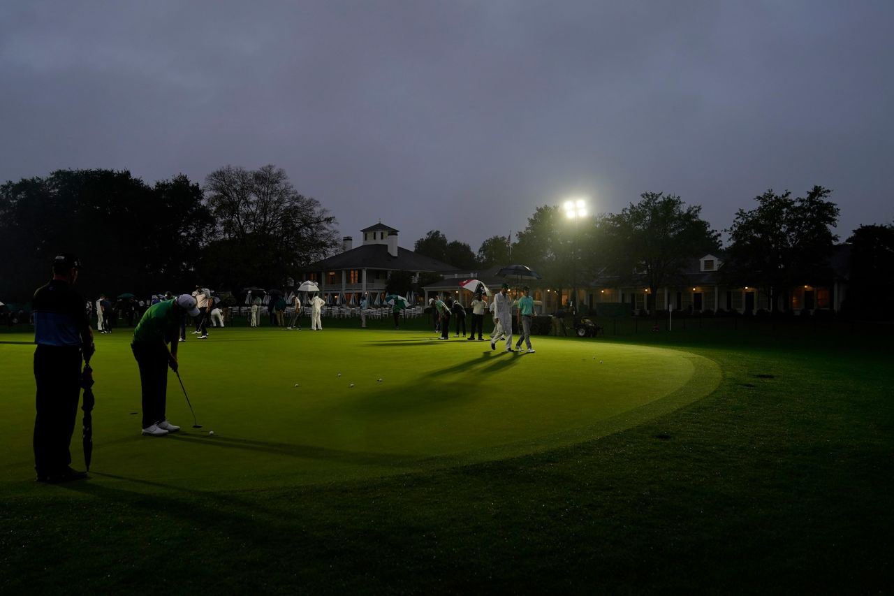 Golfers practice on the putting green next near the Augusta National Golf Course clubhouse before the start of the first round in near darkness. 