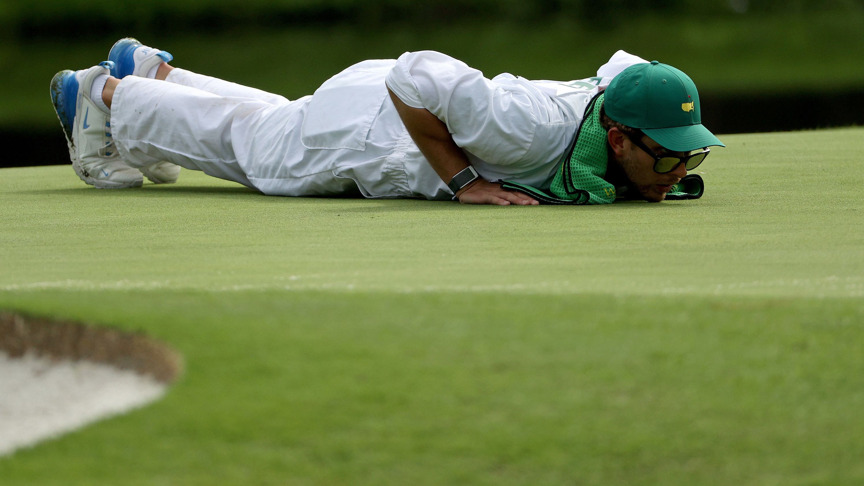 Kessler Karain, caddie for Patrick Reed, lines up a putt for the American. 