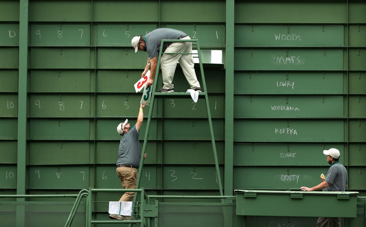 Course workers fill the scoreboard on the 15th hole during the first round.