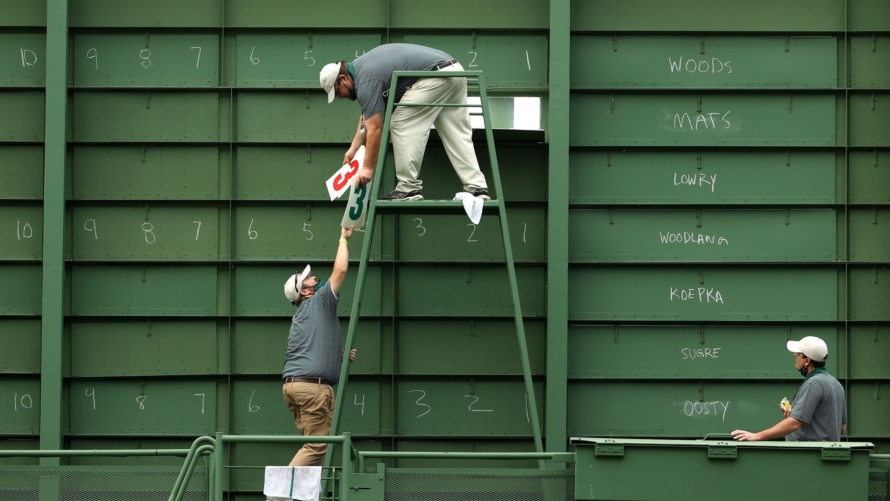 Course workers fill the scoreboard on the 15th hole during the first round.
