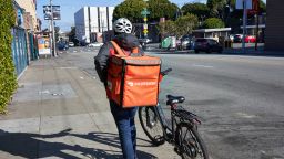A DoorDash delivery worker walks his bike along the road in the Mission neighborhood of San Francisco, California on Feb 23, 2020.