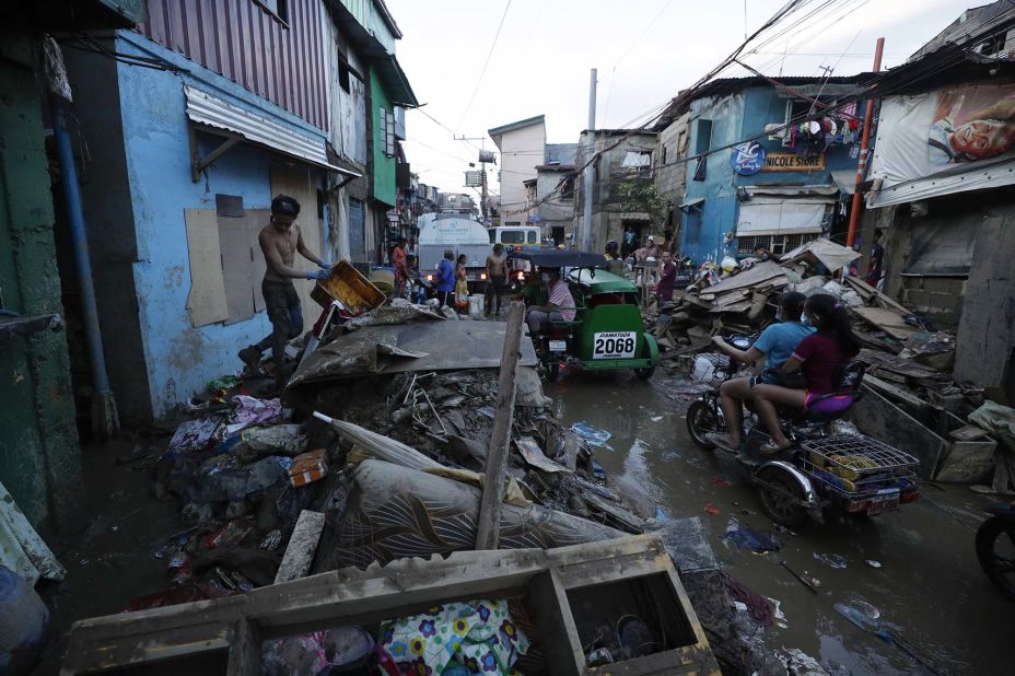 Residents ride through Marikina, Philippines, on Friday, November 13. Thick mud and debris coated many villages around the Philippine capital of Manila on Friday after Typhoon Vamco caused extensive flooding.