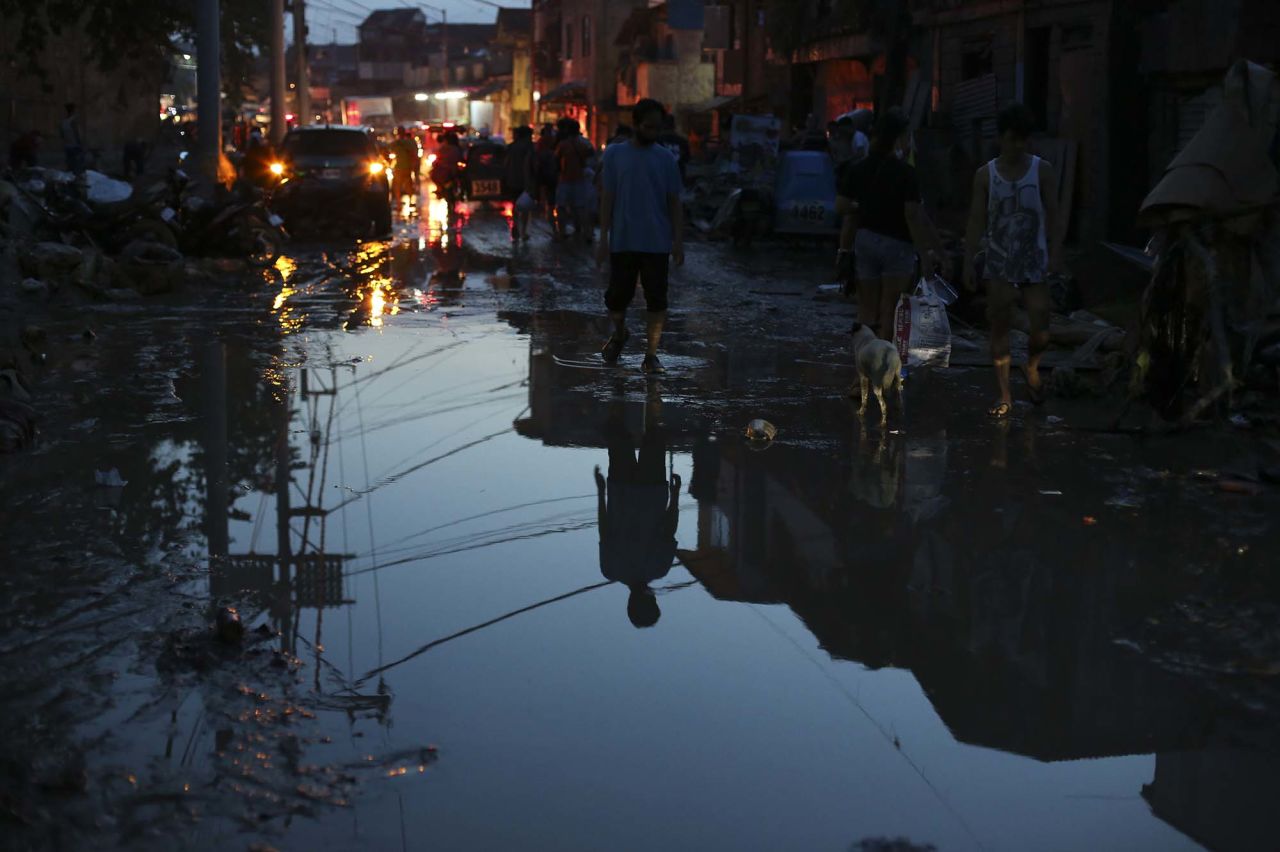 A man walks along a mud-covered road in Marikina on November 13.