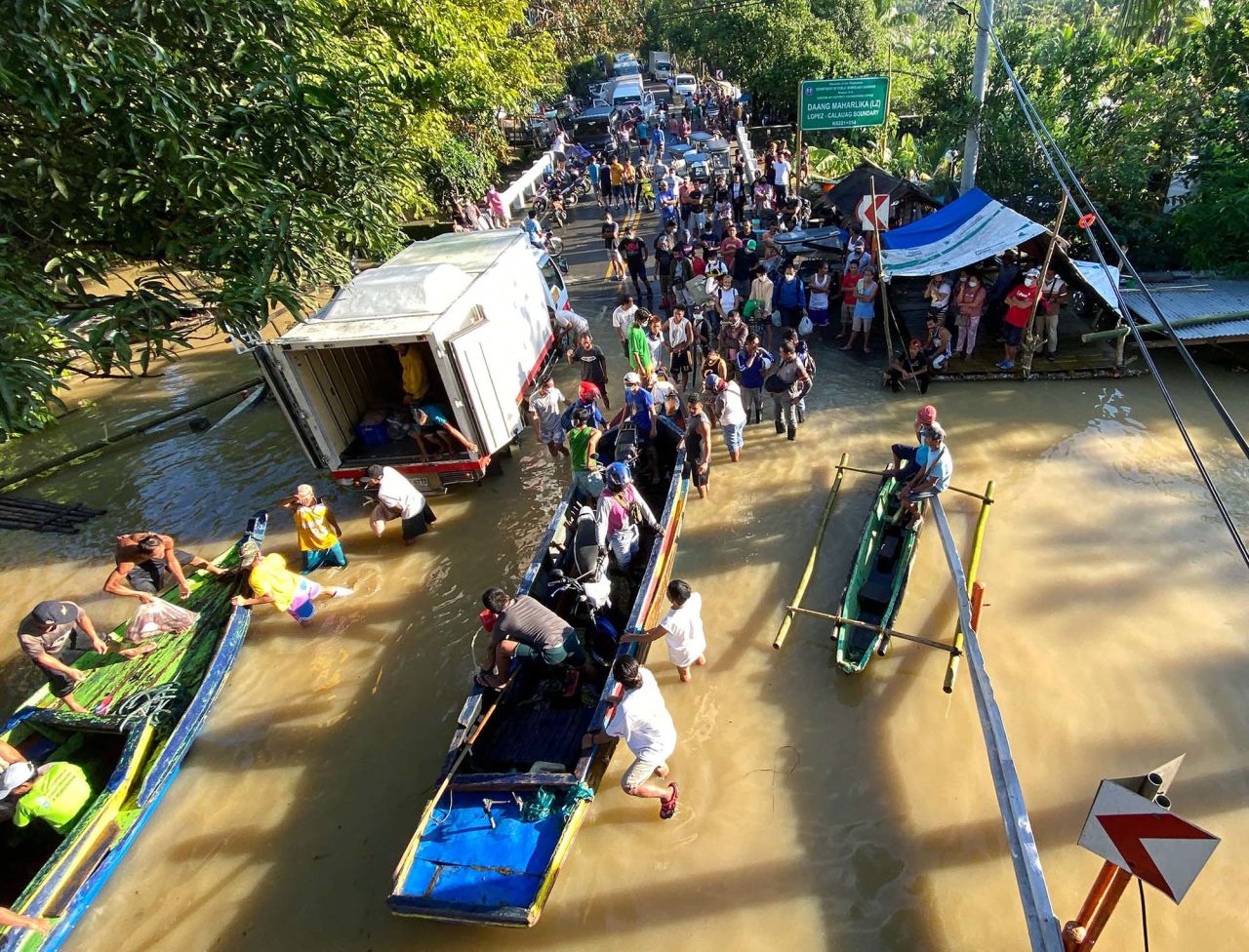 People get off a boat on a flooded road in the town of Lopez.