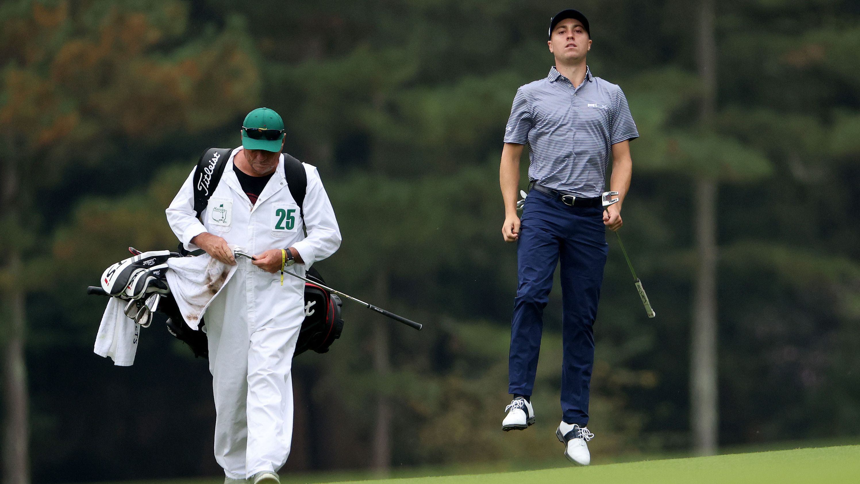 Justin Thomas of the United States jumps to check his lie on the 14th hole on his way to a 69 with four finishing birdies to share the clubhouse lead.