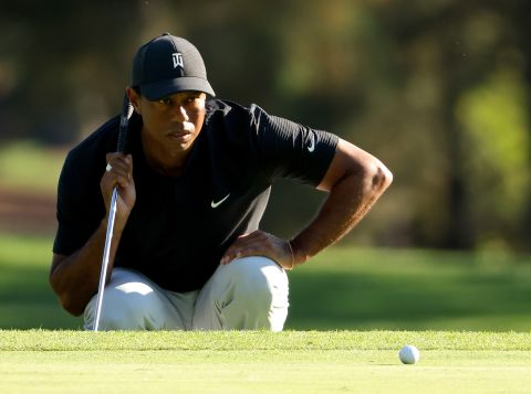 Tiger Woods of the United States lines up a putt on the third green, which he three-putted for a bogey.