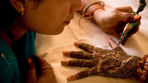 An artist applies henna to the hands of a young Indian bride.