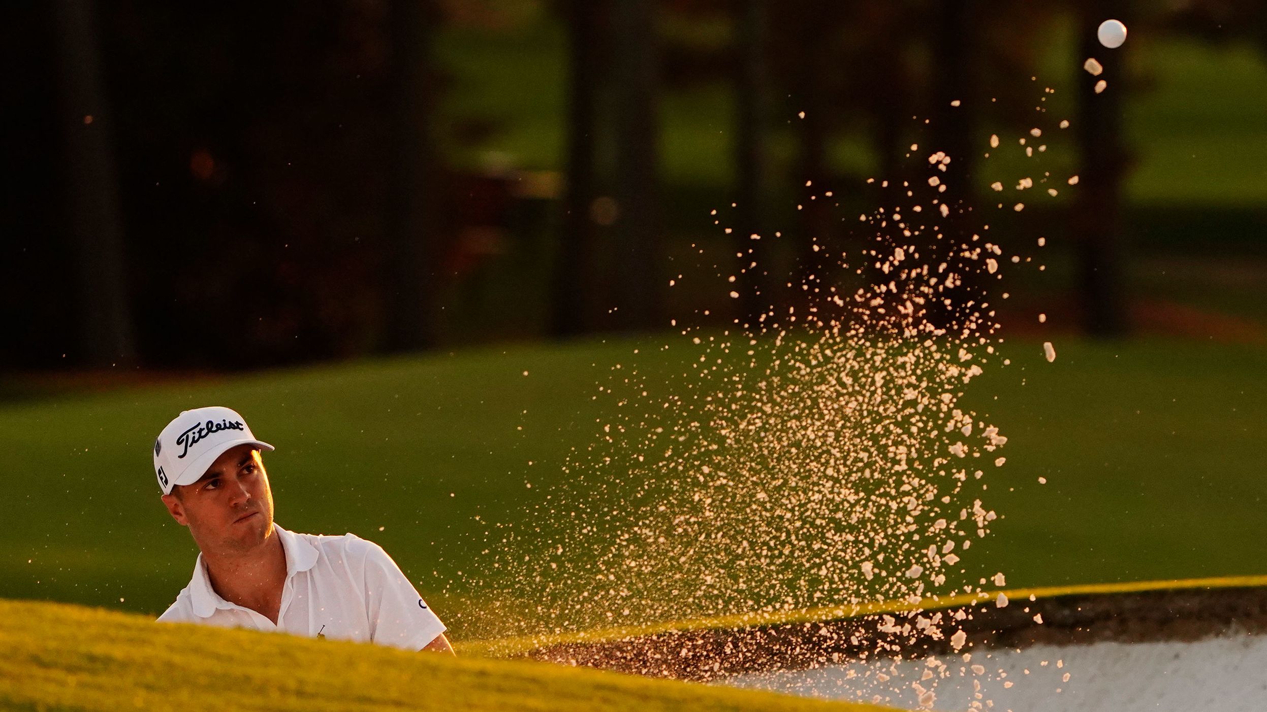 Justin Thomas watches his shot out of a bunker on the 18th hole which he eventually bogeyed to fall six behind Johnson.