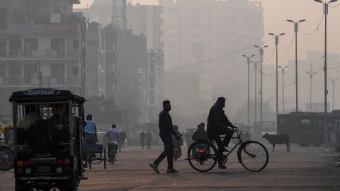 People make their way along a street amid smoggy conditions in New Delhi on November 15, 2020. 