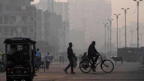 People make their way along a street amid smoggy conditions in New Delhi on November 15, 2020.