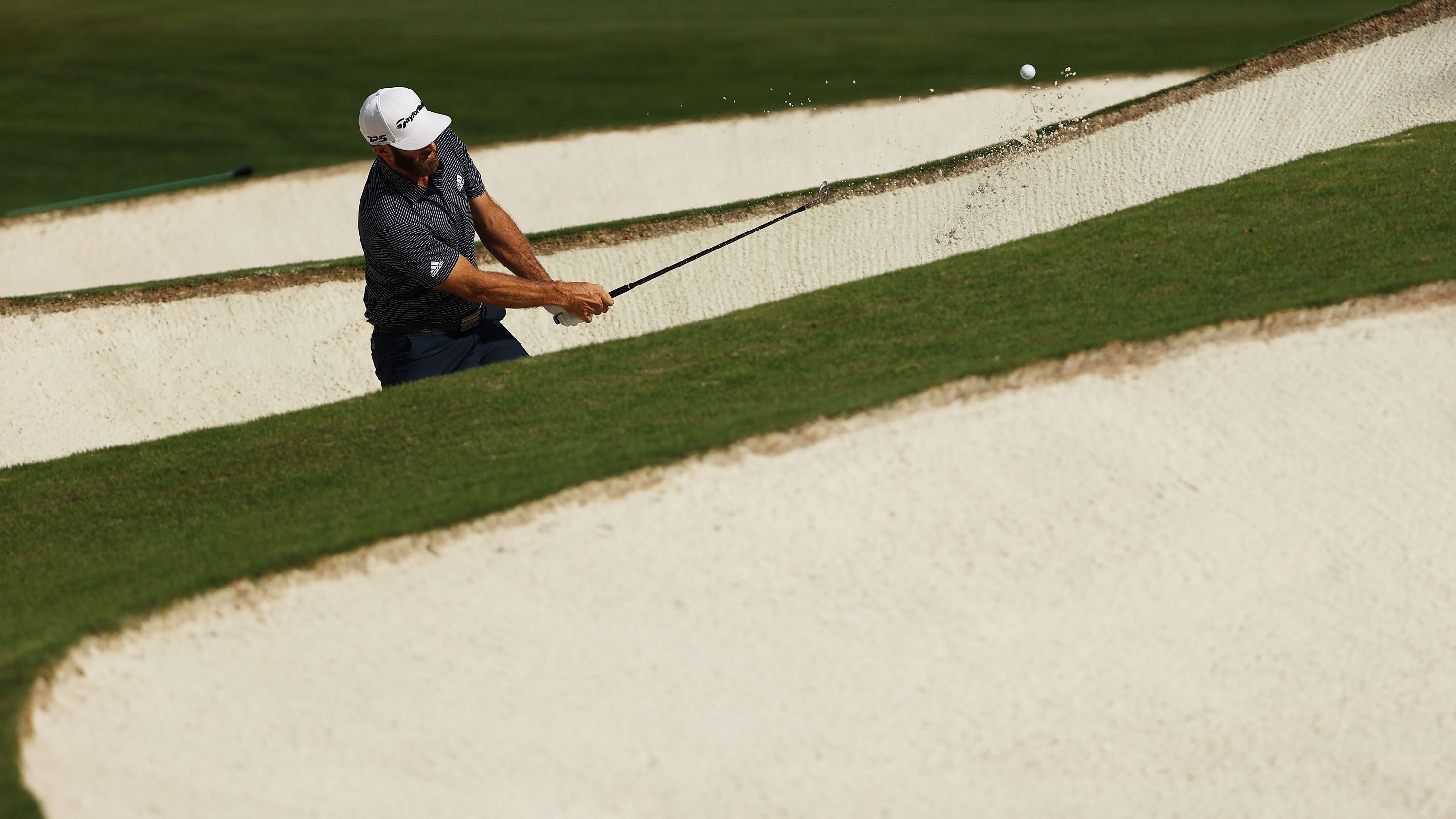 Dustin Johnson of the United States plays a shot from a bunker on the seventh hole.
