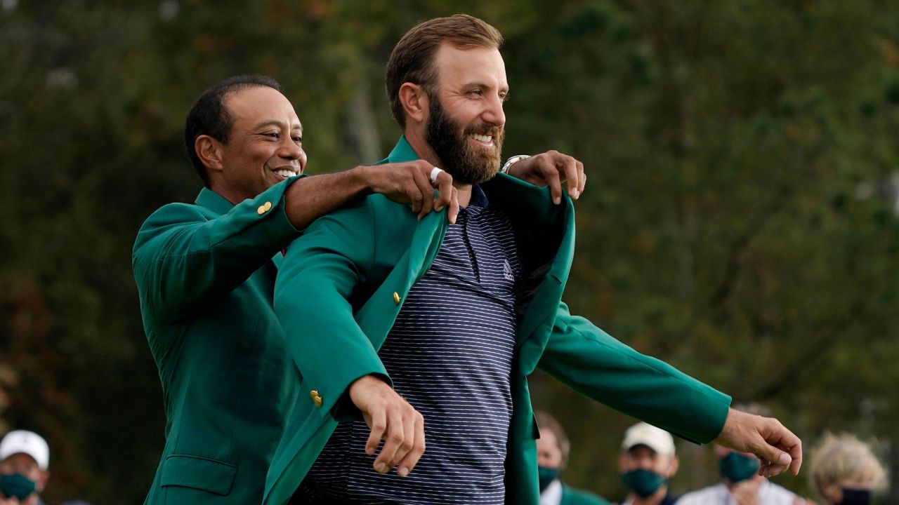 Tiger Woods helps Masters' champion Dustin Johnson with his green jacket after his victory at the Masters golf tournament Sunday, Nov. 15, 2020, in Augusta, Ga. 