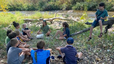 Children in Loveland, Colorado, circle around teacher Michele Mandeville during a Project Learning Tree outdoor classroom activity. 