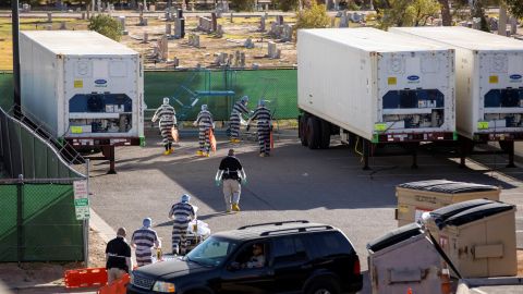 Inmates help move bodies to refrigerated trailers in El Paso County, Texas.