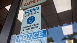 Social-distancing and mask wearing signs on a storefront during the 2020 Presidential election in Miami, Florida, U.S., on Wednesday, Nov. 4, 2020. Trump won two key states where hospitalizations for Covid-19 were among the highest in the U.S. in the past few days, Florida and Ohio, suggesting the jump in cases during the campaign may have done less harm to the Republican camp than expected. Photographer: Jayme Gershen/Bloomberg via Getty Images