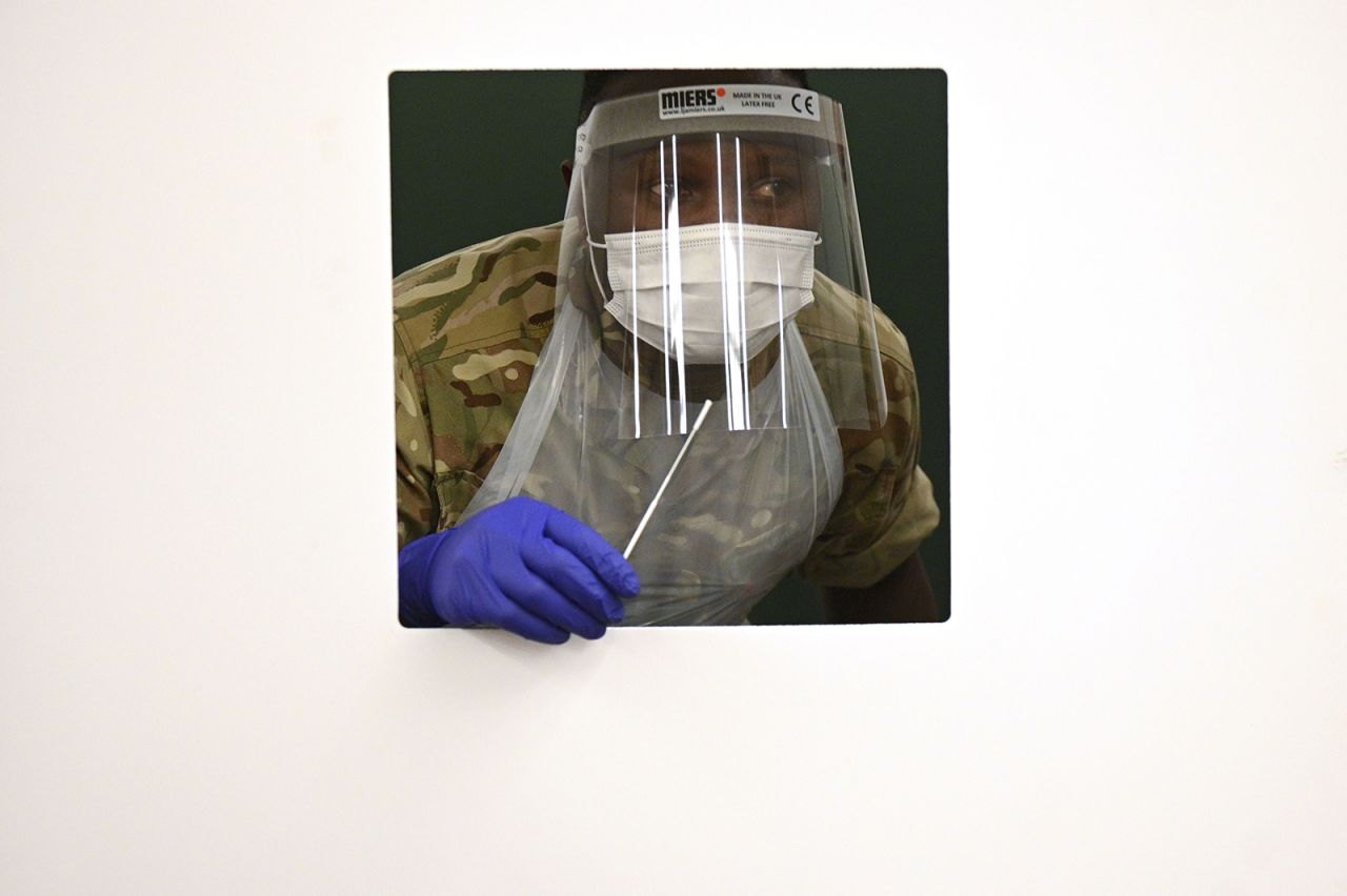 A soldier waits at a window for a colleague's swab as they practice inside a rapid testing center in Liverpool, England, on November 6.