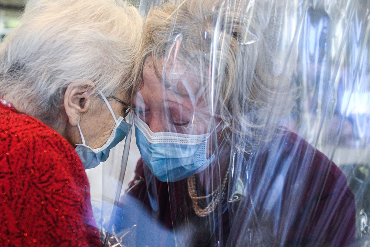 A nursing-home resident, left, speaks with her visiting daughter through a plastic screen in Castelfranco Veneto, Italy, on November 11. The plastic screen is part of a "Hug Room" that allows residents and their families to embrace each other during the coronavirus pandemic.