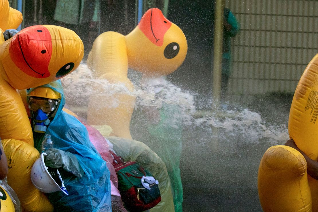 Pro-democracy protesters take cover with inflatable ducks as police fire water cannons during an anti-government rally near the Parliament in Bangkok, on November 17, 2020. 