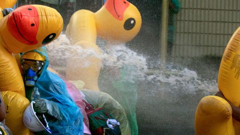 Pro-democracy protesters take cover with inflatable ducks as police fire water cannons during an anti-government rally near the Parliament in Bangkok, on November 17, 2020. 