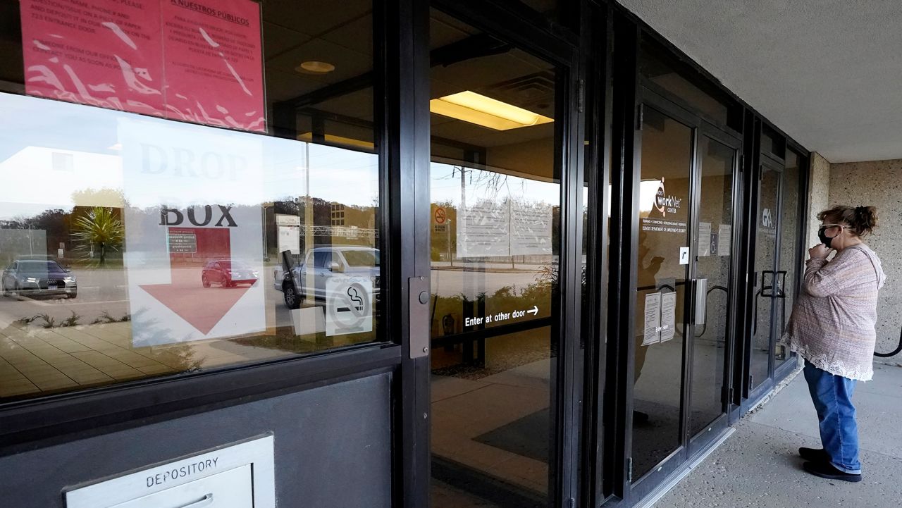 A woman checks information as information signs are displayed at IDES (Illinois Department of Employment Security) WorkNet center in Arlington Heights, Ill., Thursday, Nov. 5, 2020. Illinois reports biggest spike in unemployment claims of all states. (AP Photo/Nam Y. Huh)