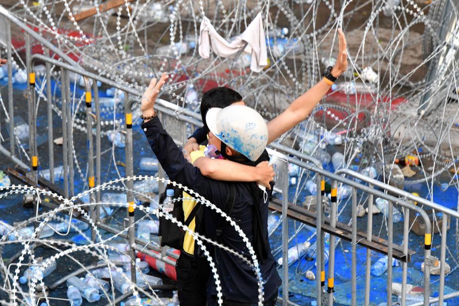 A pro-democracy protester and royalist supporter embrace and gesture to other protesters, during a rally in Bangkok on November 17.