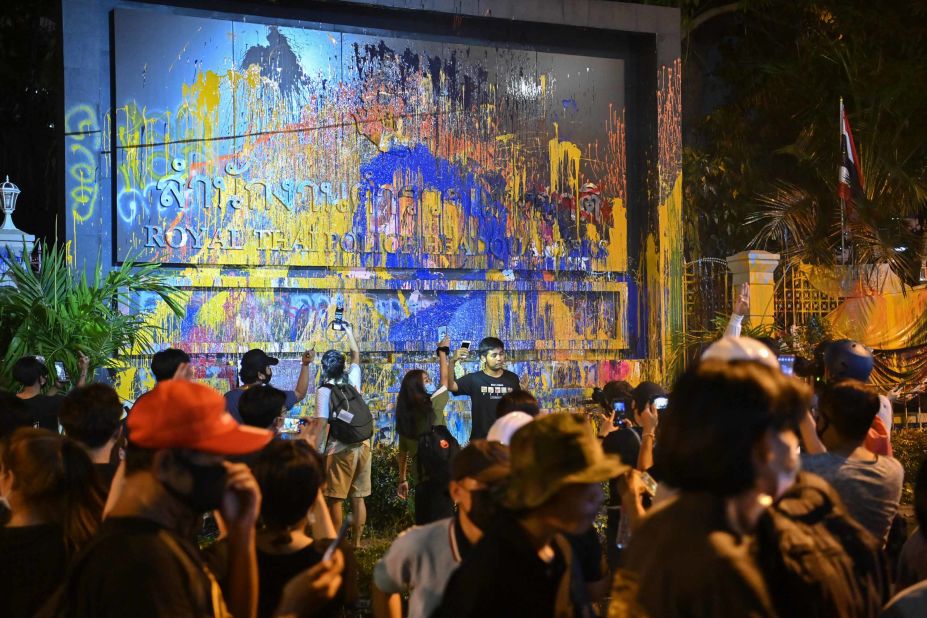 Pro-democracy protesters pose for photos next to the paint-splattered sign for the police headquarters in Bangkok on November 18.