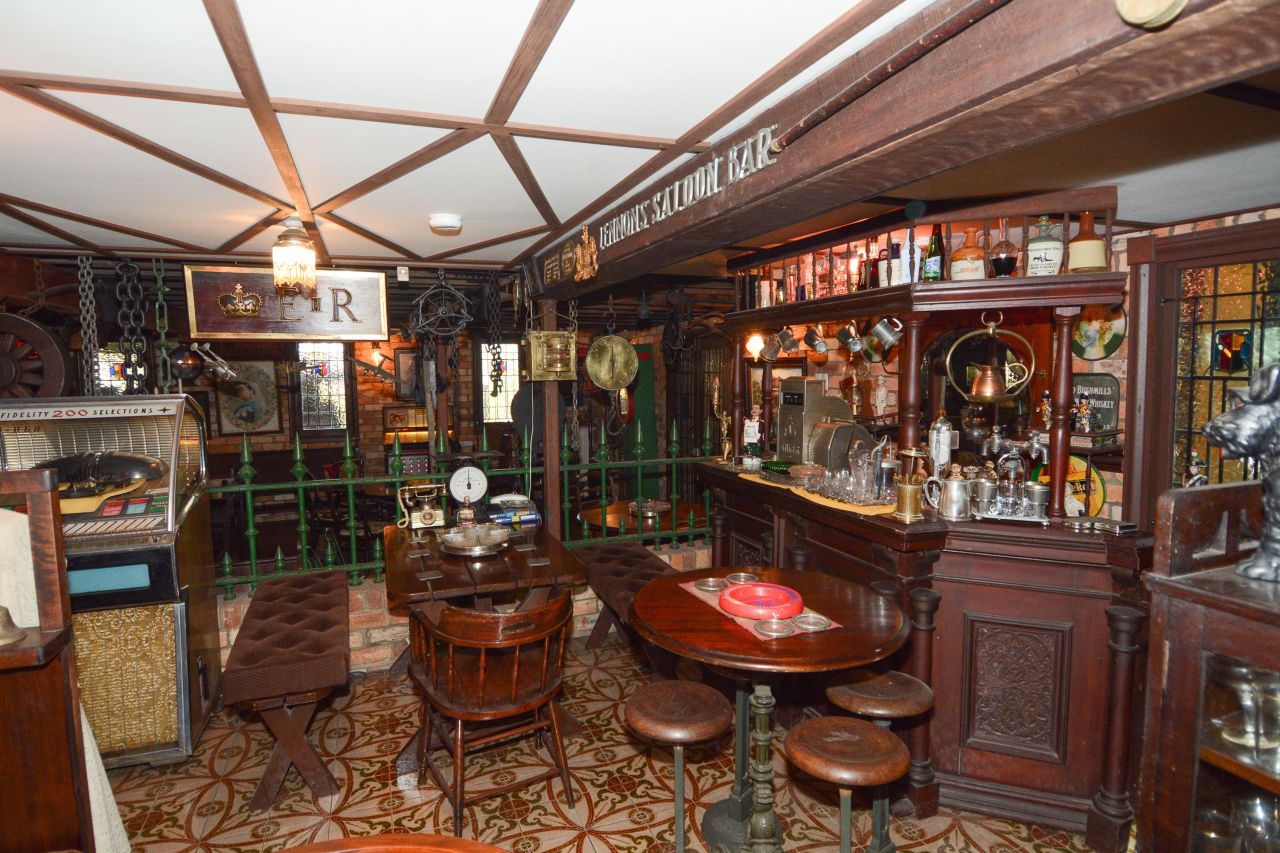 Alan Brough had modeled part of the room on a traditional British saloon bar. An antique Anker cash register sat on the counter surrounded by glassware and silver tankards.