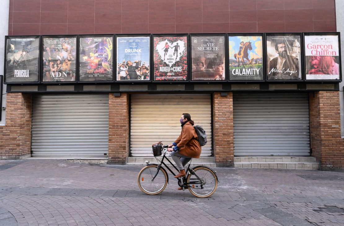 A woman rides a bicycle past a closed cinema in Montpellier, southern France, on November 16.