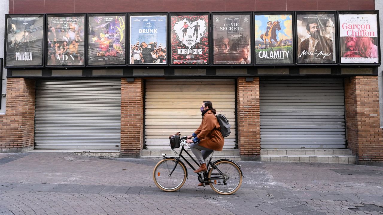 A woman rides a bicycle past a closed cinema in Montpellier, southern France, on November 16.
