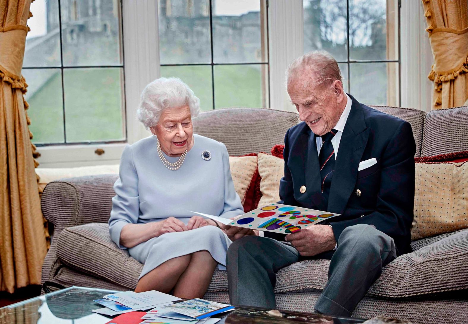 The Queen and Prince Philip look at a homemade anniversary card that was given to them by their great-grandchildren Prince George, Princess Charlotte and Prince Louis in November 2020.