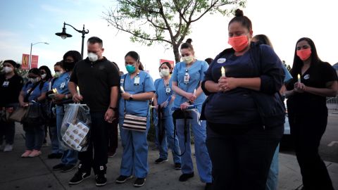 Health care workers bow their heads at a vigil in California for Celia Marcos, a nurse who died two days after testing positive for coronavirus. Marcos, a Filipina nurse who died in April, is one of the fallen nurses mentioned in a recent report by the nation's largest nurses' union.