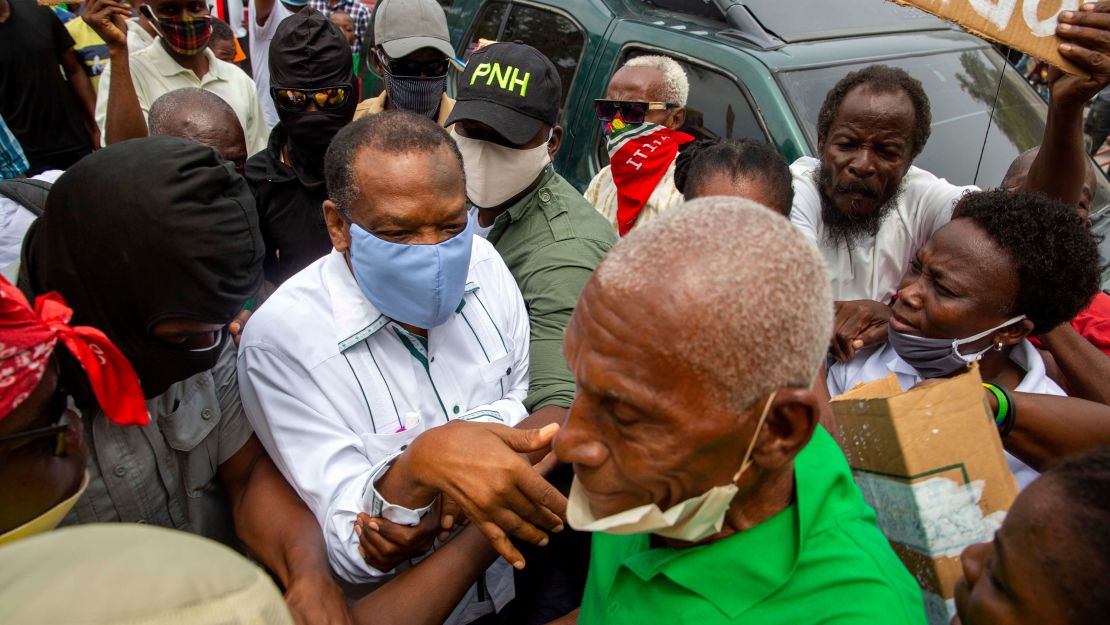 Yves Jean-Bart, wearing a light blue protective face mask, arrives at a courthouse for a hearing regarding allegations that he abused female athletes at the country's national training center in Croix-des-Bouquets, Haiti.