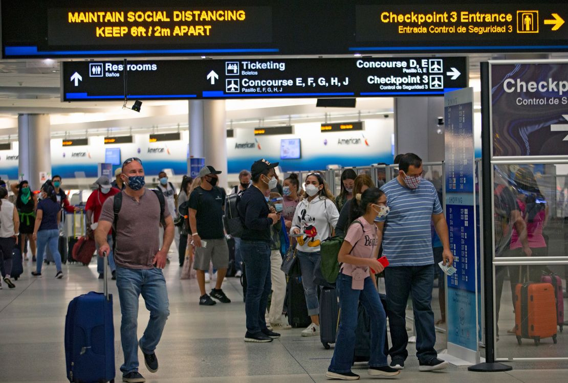 Travelers wearing protective face masks walking through Miami International Airport on Sunday.