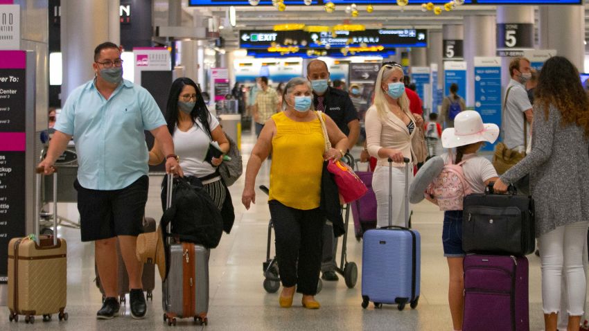 Travelers wearing protective face masks walking through Concourse D at the Miami International Airport on Sunday, Nov. 22, 2020, in Miami, Fla. With the coronavirus surging out of control, the nation's top public health agency pleaded with Americans not to travel for Thanksgiving and not to spend the holiday with people from outside their household. (David Santiago/Miami Herald via AP)