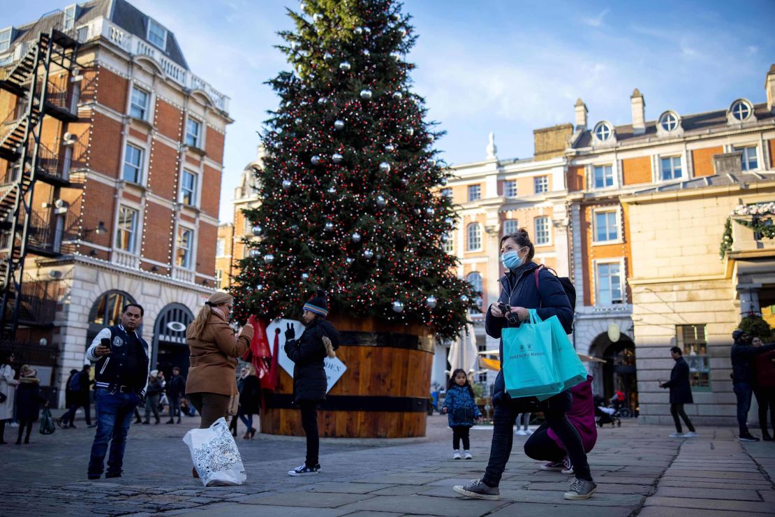 Pedestrians wearing masks pass a Christmas tree in Covent Garden in central London on November 22, during England's four-week national lockdown.