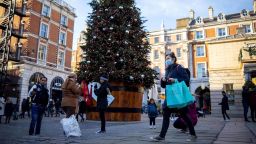 Pedestrians wearing a protective face covering to combat the spread of the coronavirus, walk past a Christmas tree in Covent Garden in central London, on November 22, 2020, as the four-week national shutdown imposed in England continues, forcing people to stay home and businesses to close owing to a second wave of the Covid-19 pandemic. - British Prime Minister Boris Johnson will confirm that coronavirus lockdown restrictions across England are to end on December 2, his office said Saturday. The lockdown will be followed by a return to a three-tiered set of regional restrictions as part of the government's "COVID Winter Plan", it added in a statement. (Photo by Tolga Akmen / AFP) (Photo by TOLGA AKMEN/AFP via Getty Images)