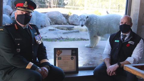 Canadian Army Brig. Gen. Conrad Mialkowski and Toronto Zoo CEO Dolf DeJong display Juno's certificate of appreciation with the 5-year-old bear in the background.