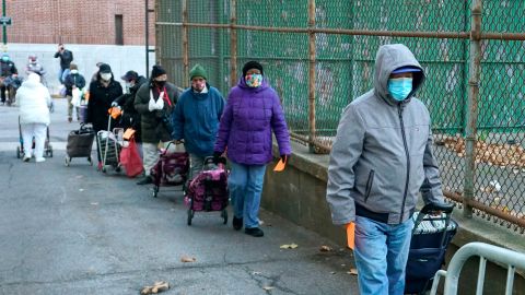 People line up for food before a event where Archbishop of New York Timothy Cardinal Dolan handed out turkeys, during the Catholic Charities annual Thanksgiving meal distribution event at the Kennedy Center in Harlem, New York on November 24, 2020. (Photo by TIMOTHY A. CLARY / AFP) (Photo by TIMOTHY A. CLARY/AFP via Getty Images)