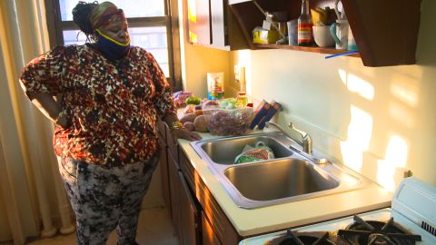 Regina Status stands in her kitchen with food from the Agatha House Foundation in the Bronx.