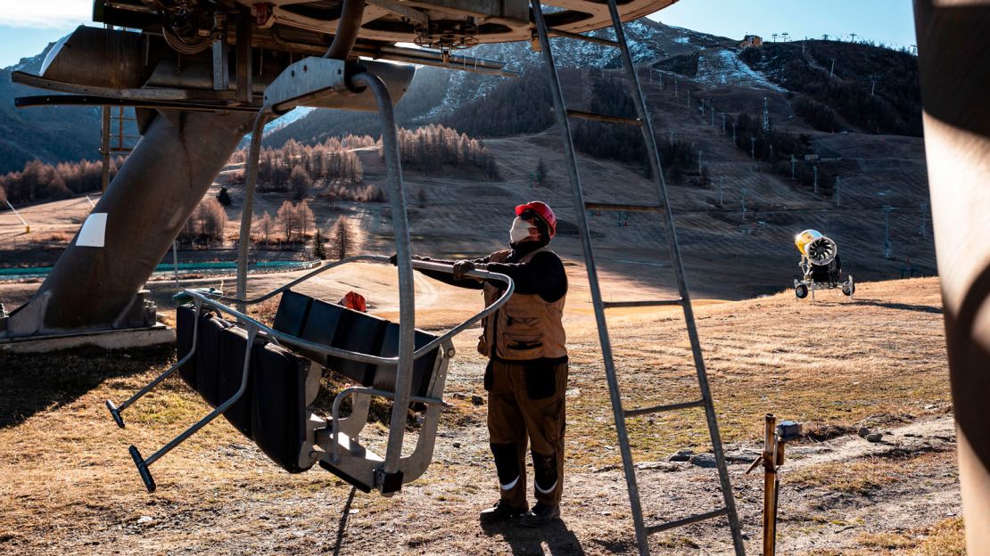 A staff member at alpine ski resort Sestriere in Piedmont, Italy wears a face mask while checking chair lifts.