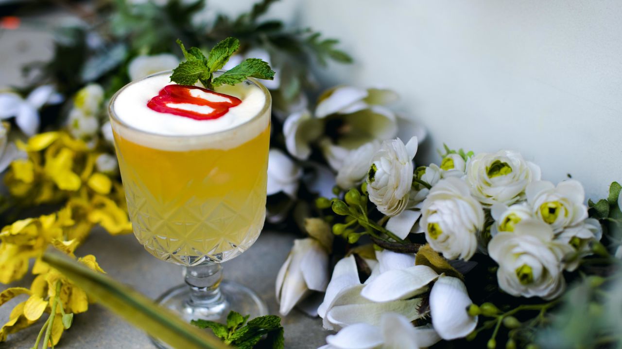 A customised craft cocktail from Sidecar's "All things gin" menu: orange bitters, sugar and lime, topped with egg white foam and garnished with fresh red bell pepper.