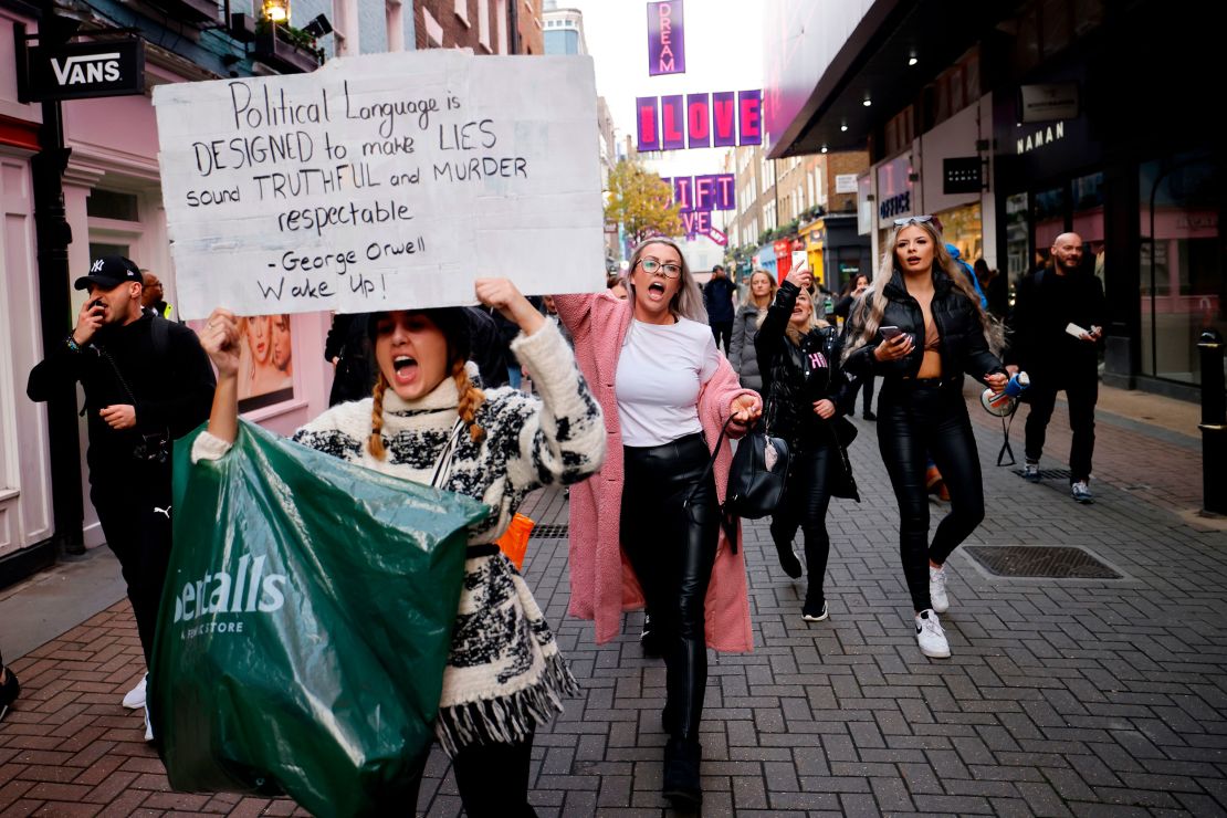 Protesters hold up placards as they take part in an anti-lockdown protest against government restrictions designed to control or mitigate the spread of the novel coronavirus, including the wearing of masks and lockdowns, in London on November 28, 2020.