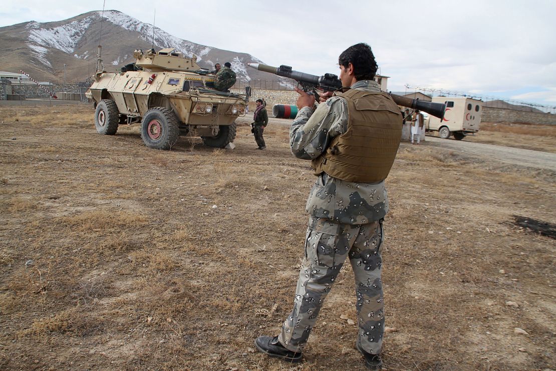 A member of security personnel holds a rocket-propelled grenade near the site of the car bomb.