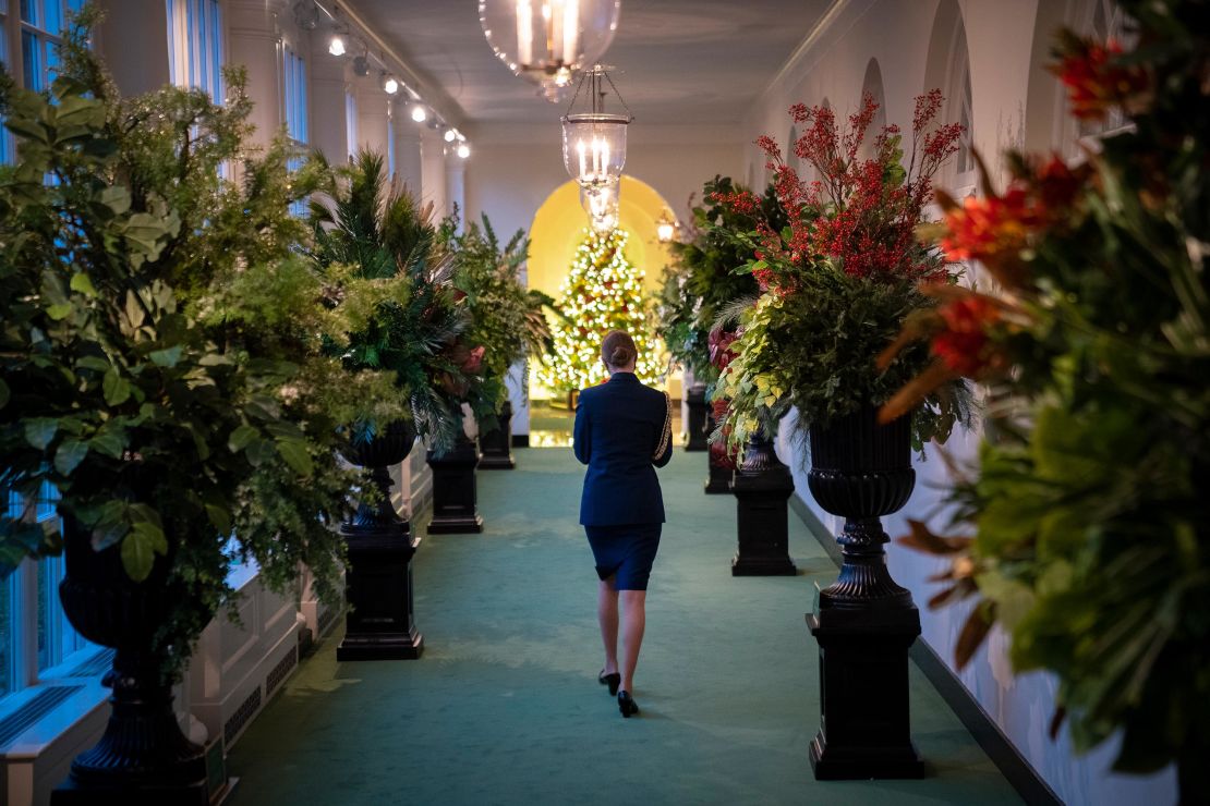 A military aide walks between Christmas decorations in the East Wing of the White House on Monday.
