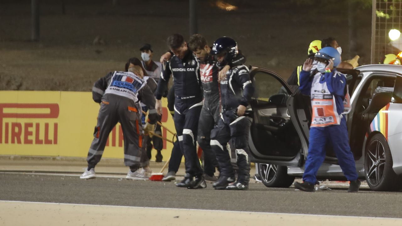 Romain Grosjean is helped away from his car following a crash at the Bahrain GP.