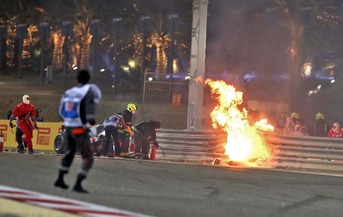 Race officials put out the fire on Grosjean's car at the Bahrain GP.