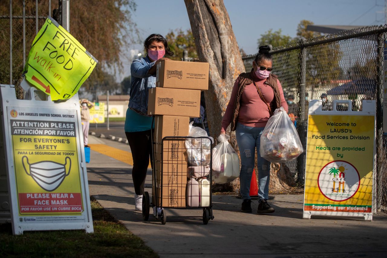 Two women take home free meals after waiting in a long line at a high school in South Gate, California, on November 25.