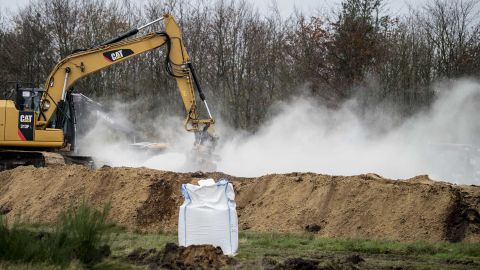 A bag of calcium oxide is seen in the foreground as an excavator buries dead mink in ditches in a military area near Holstebro, Denmark on Monday, November 9, 2020. 